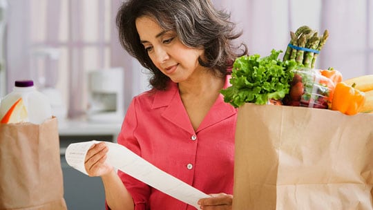 Woman reviews high grocery prices on receipt